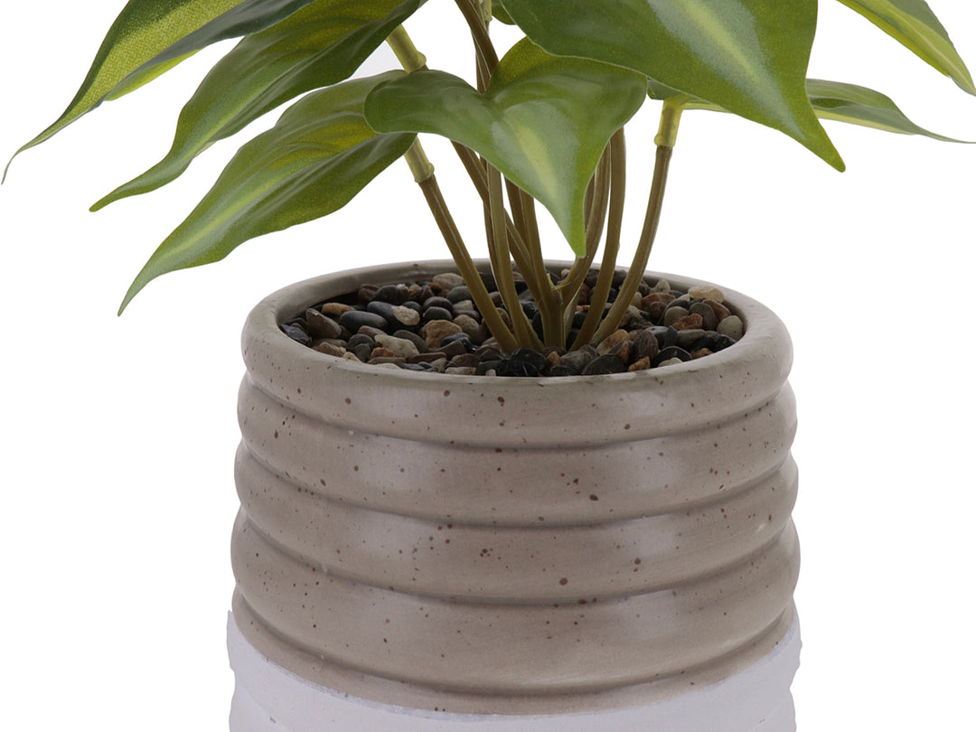 Planta artificial verde en maceta decorativa de cerámica color beige con diseño ondulado y base blanca.