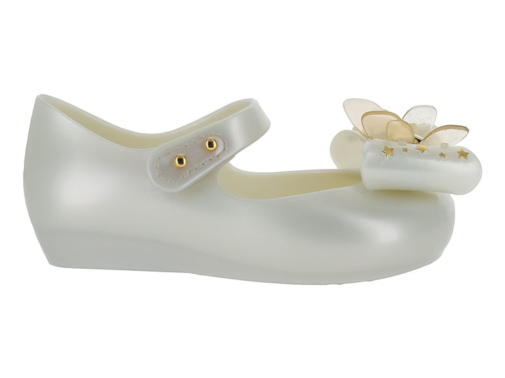 Zapato blanco brillante para niña de Mini Melissa con correa y adorno de moño con estrellas doradas.