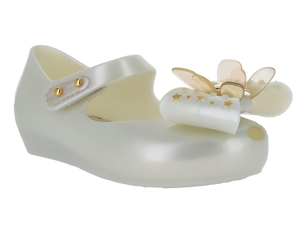 Zapato blanco brillante para niña de Mini Melissa con correa y adorno de moño con estrellas doradas.