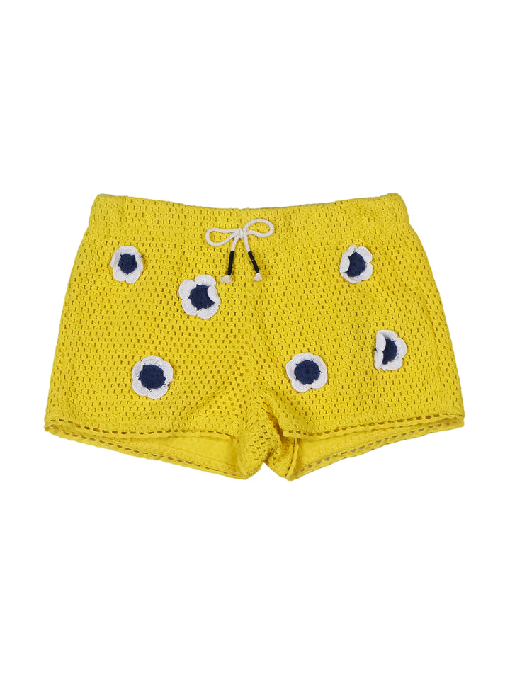 Short amarillo para niña con aplicaciones de flores blancas y azules y cordón ajustable en la cintura.