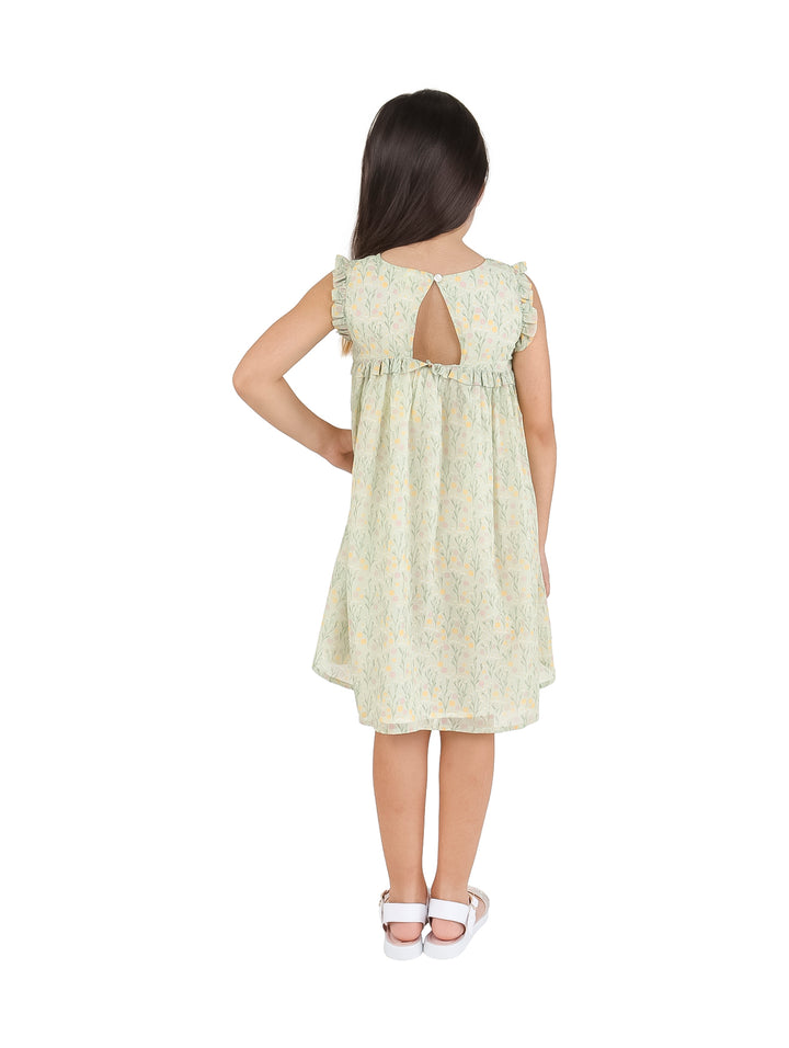Niña vistiendo un vestido corto color verde agua con estampado floral amarillo y sandalias blancas.