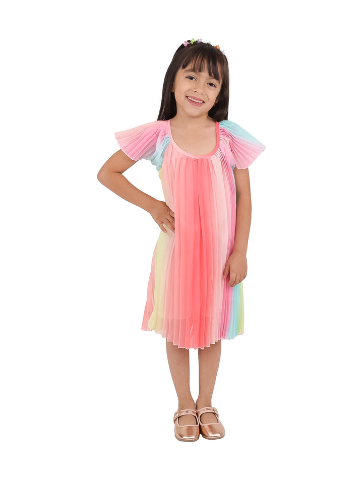 Niña vistiendo un vestido corto de tul plisado en colores arcoíris con predominancia del rosa.