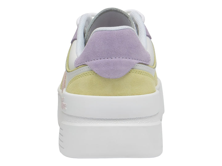 Tenis Lacoste blancos con detalles en morado y amarillo y suela de plataforma blanca.