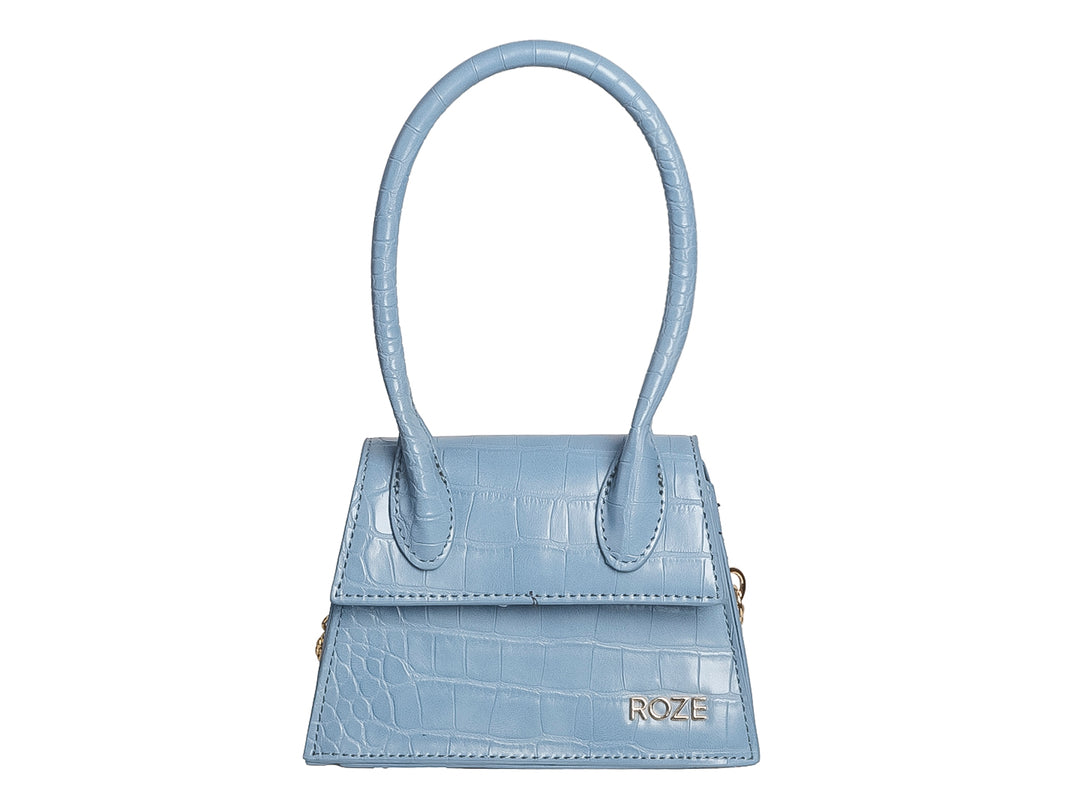 Bolso de mano color azul claro con textura de cocodrilo y asa circular alta.