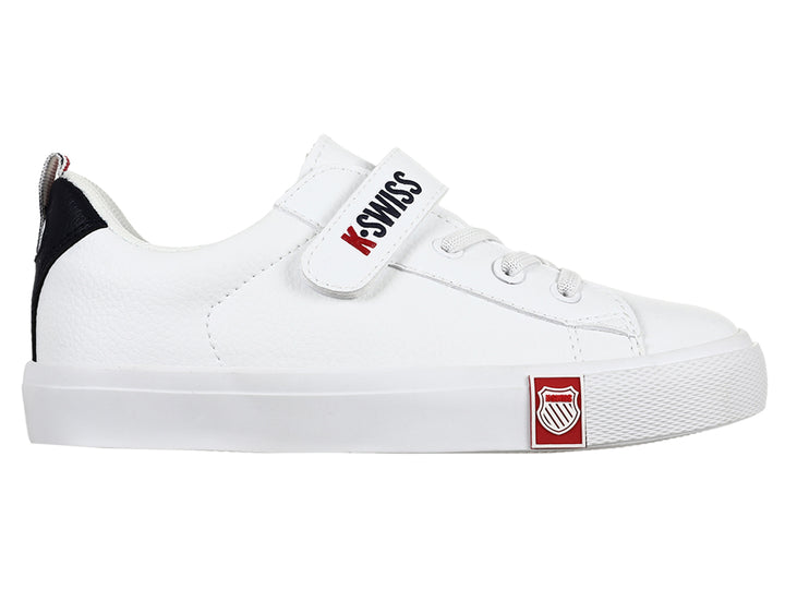 Tenis K-Swiss blancos para niño con cierre de velcro y detalle negro en el talón.