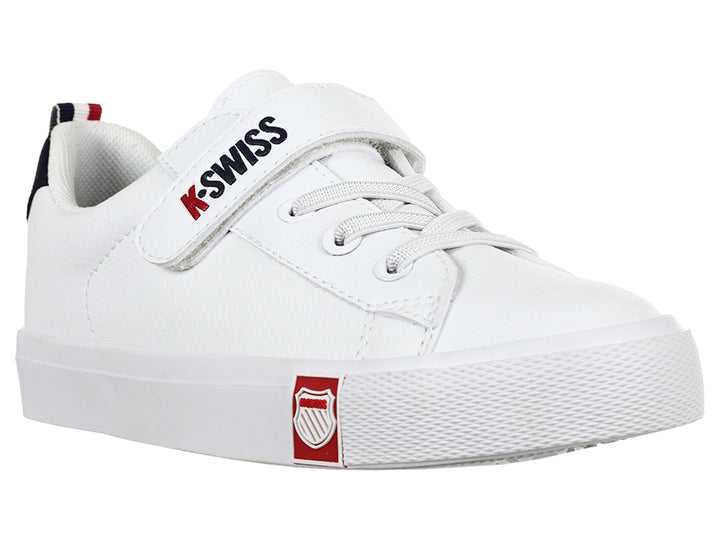 Tenis K-Swiss blancos para niño con cierre de velcro y detalle negro en el talón.