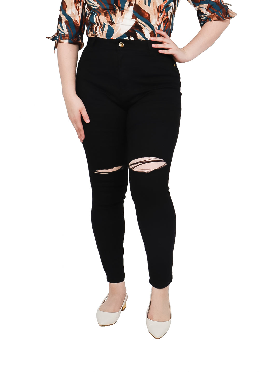 Mujer vistiendo pantalones jeans negros ajustados con roturas en las rodillas y talle alto.