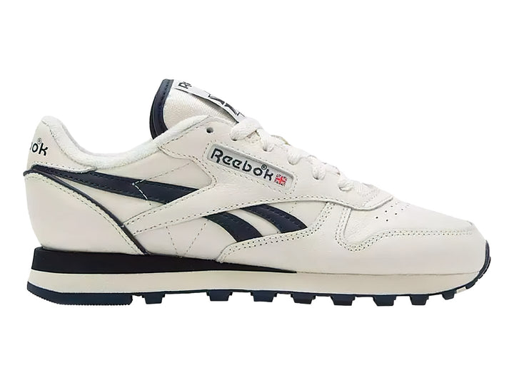 Tenis Reebok Classic Leather en color blanco con detalles en azul marino y suela blanca y azul.