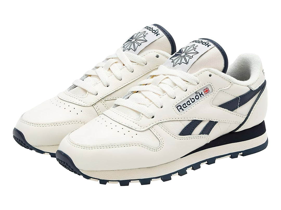 Tenis Reebok Classic Leather en color blanco con detalles en azul marino y suela blanca y azul.