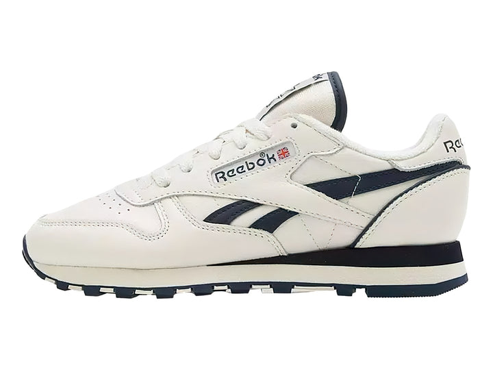 Tenis Reebok Classic Leather en color blanco con detalles en azul marino y suela blanca y azul.