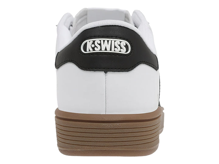 Tenis K-Swiss blancos con rayas negras laterales, punta gris y suela color café.