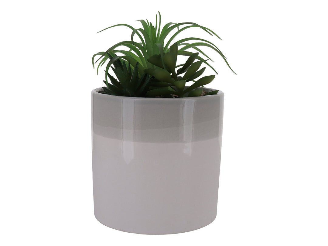 Planta artificial verde en maceta cilíndrica de cerámica bicolor blanco y beige con acabado brillante.