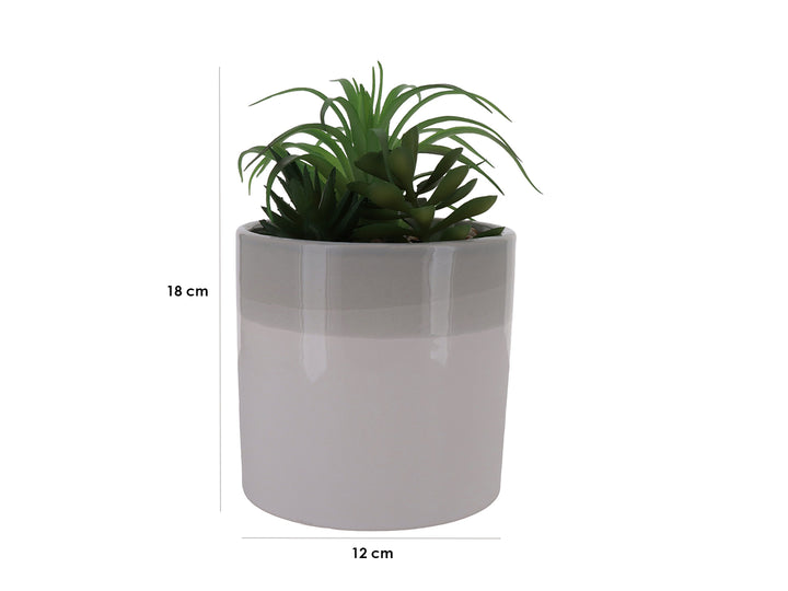 Planta artificial verde en maceta cilíndrica de cerámica bicolor blanco y beige con acabado brillante.