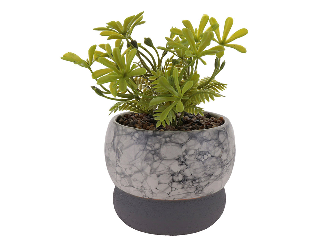 Planta artificial decorativa en maceta de cerámica con acabado de mármol blanco y base gris oscuro.