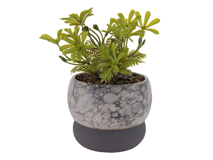 Planta artificial decorativa en maceta de cerámica con acabado de mármol blanco y base gris oscuro.