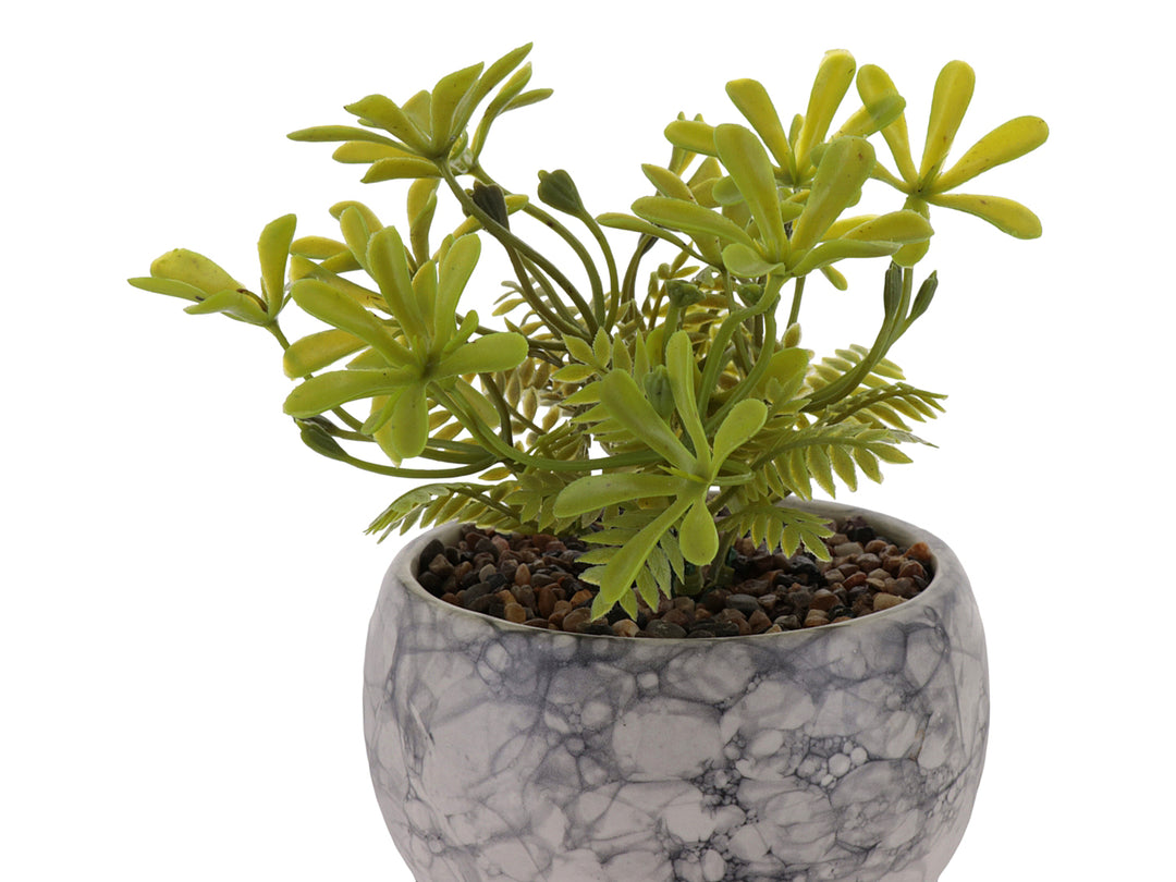 Planta artificial decorativa en maceta de cerámica con acabado de mármol blanco y base gris oscuro.