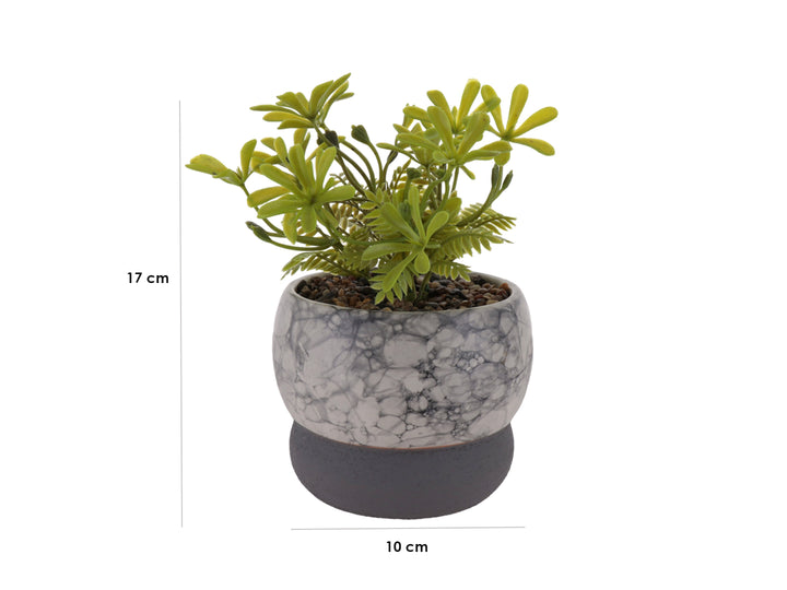 Planta artificial decorativa en maceta de cerámica con acabado de mármol blanco y base gris oscuro.