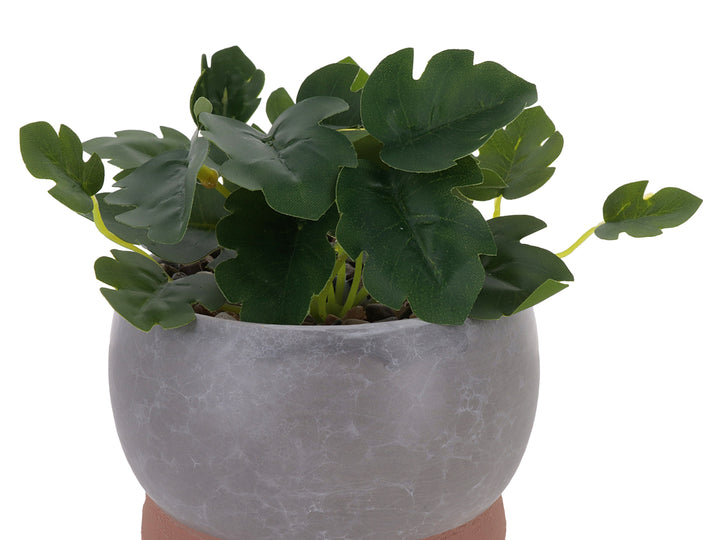 Planta artificial en maceta decorativa de dolomita con acabado en mármol gris y base marrón.