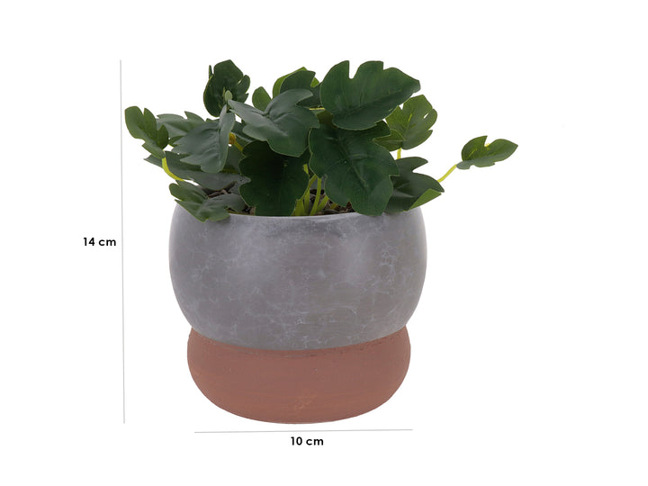 Planta artificial en maceta decorativa de dolomita con acabado en mármol gris y base marrón.