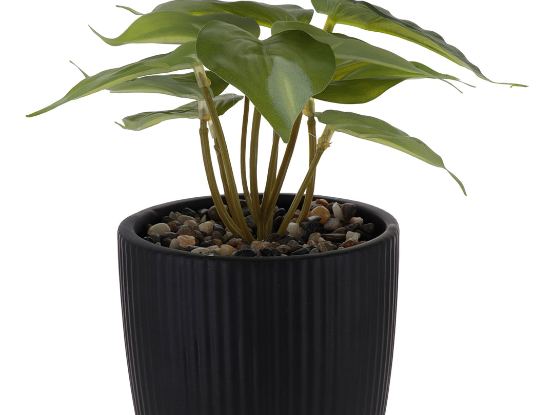 Planta artificial verde en maceta decorativa de dolomita color negro con textura acanalada y base redondeada.