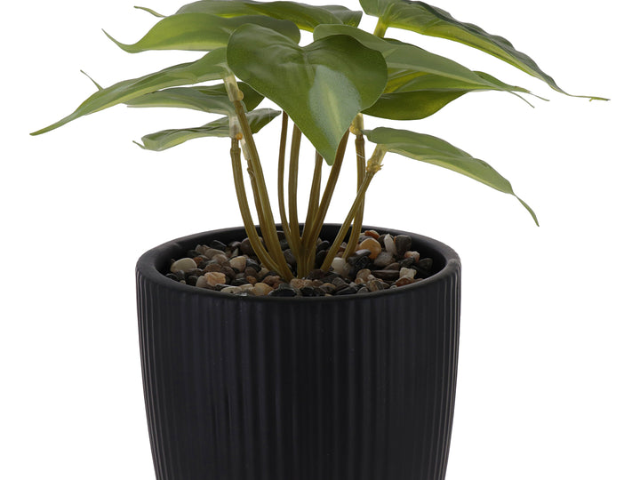 Planta artificial verde en maceta decorativa de dolomita color negro con textura acanalada y base redondeada.