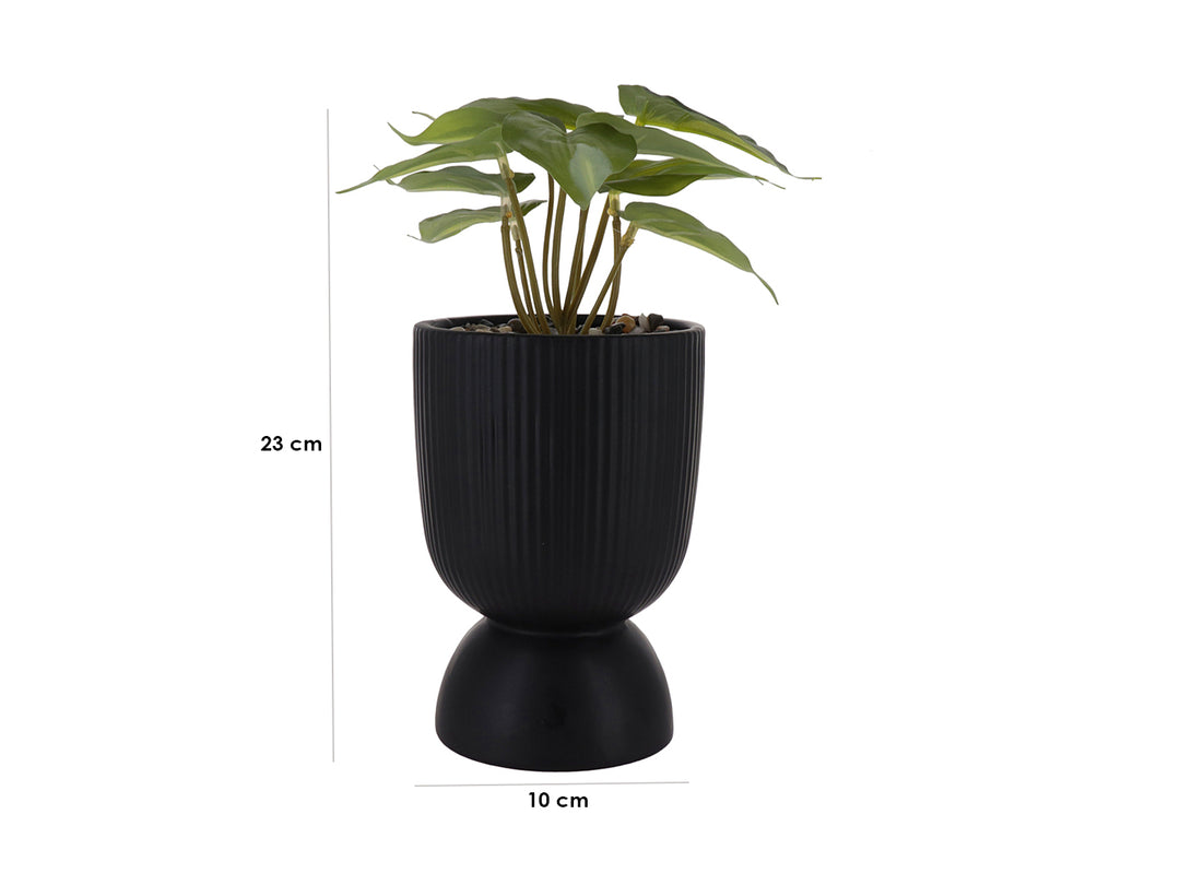Planta artificial verde en maceta decorativa de dolomita color negro con textura acanalada y base redondeada.