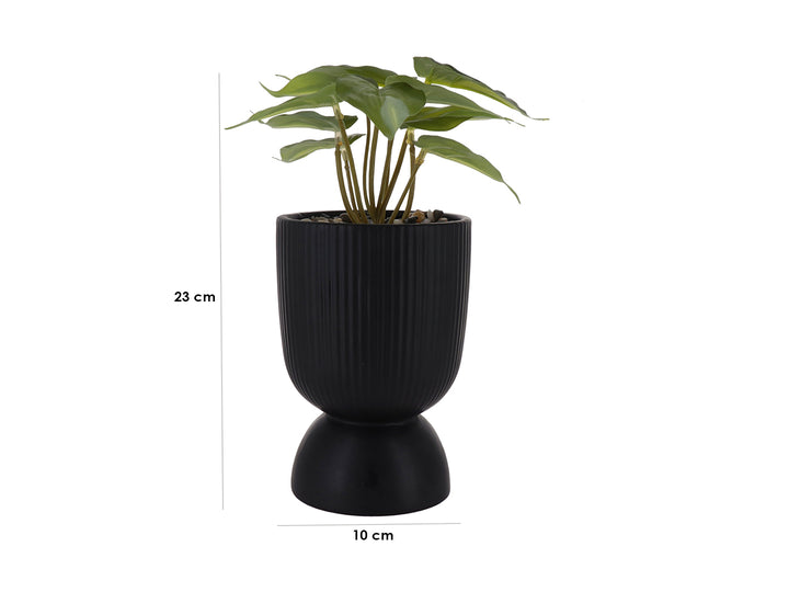 Planta artificial verde en maceta decorativa de dolomita color negro con textura acanalada y base redondeada.