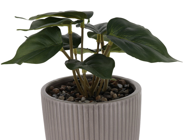 Planta artificial verde en maceta decorativa de dolomita color beige con diseño acanalado y base redondeada.
