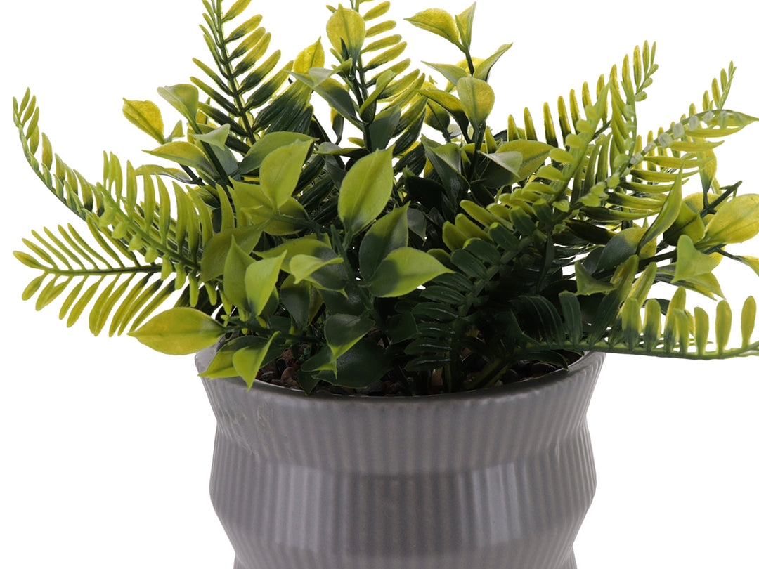 Planta artificial verde en maceta de dolomita gris con diseño acanalado.