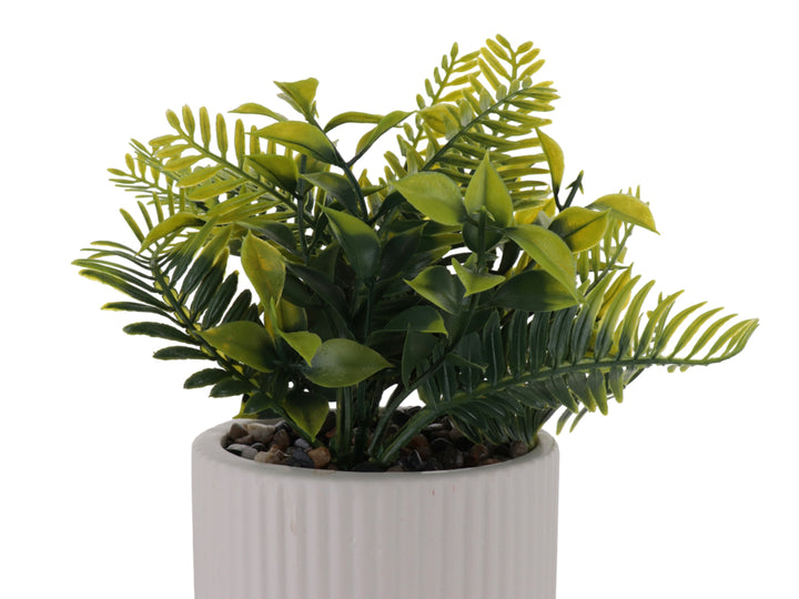 Planta artificial verde en maceta decorativa de dolomita blanca con textura acanalada.