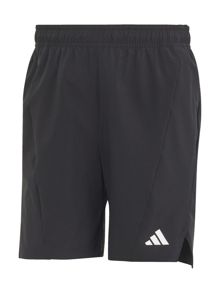 Hombre realizando ejercicio con mancuernas vistiendo shorts deportivos negros de Adidas.