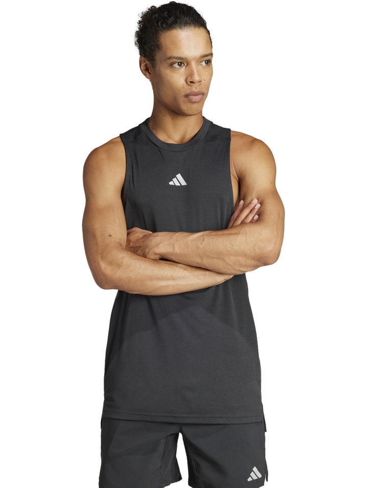 Hombre vistiendo una camiseta deportiva sin mangas de color negro con logotipo de Adidas en el pecho.