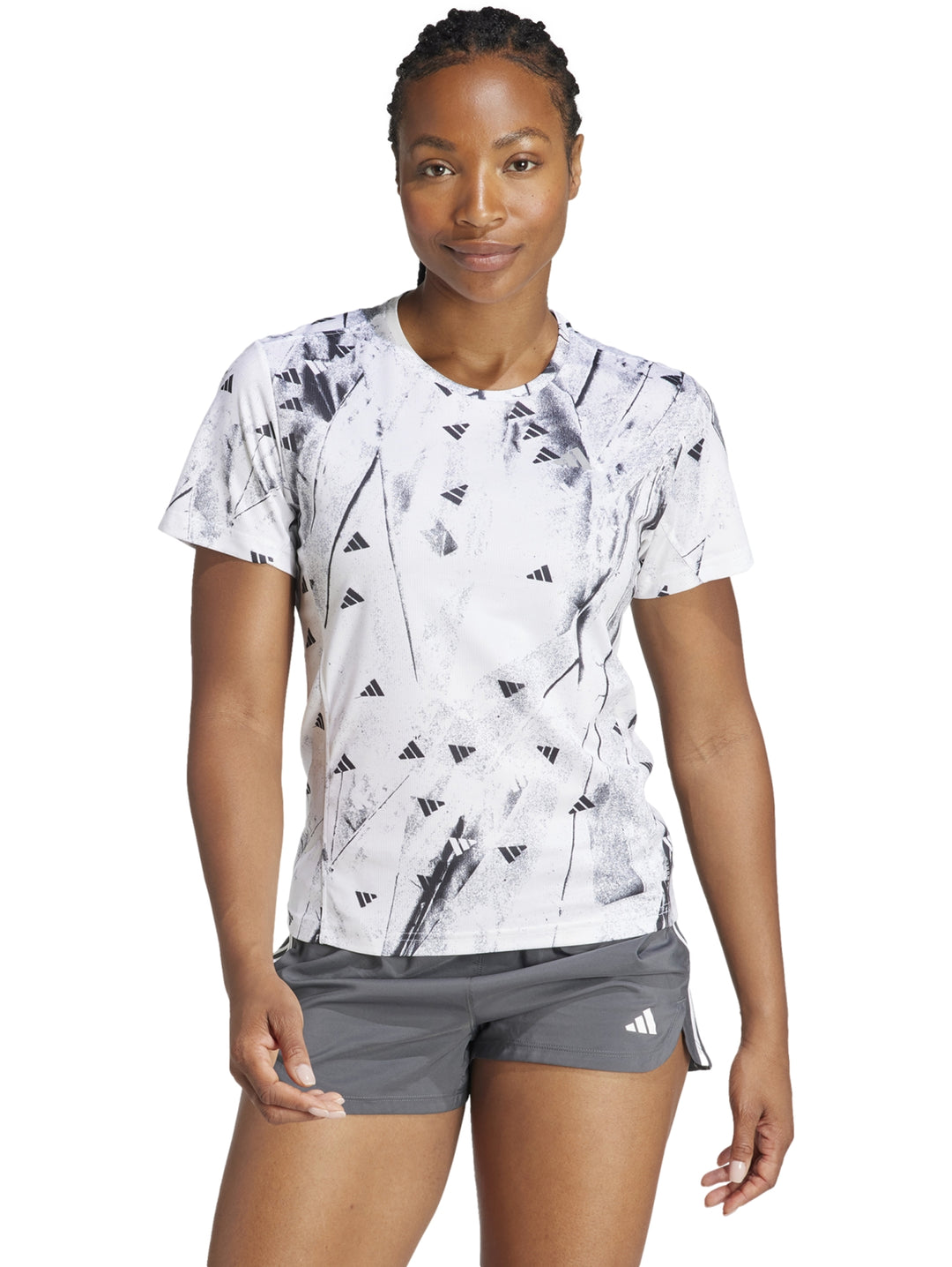 Camiseta deportiva blanca de manga corta con estampado abstracto en negro y cuello redondo.