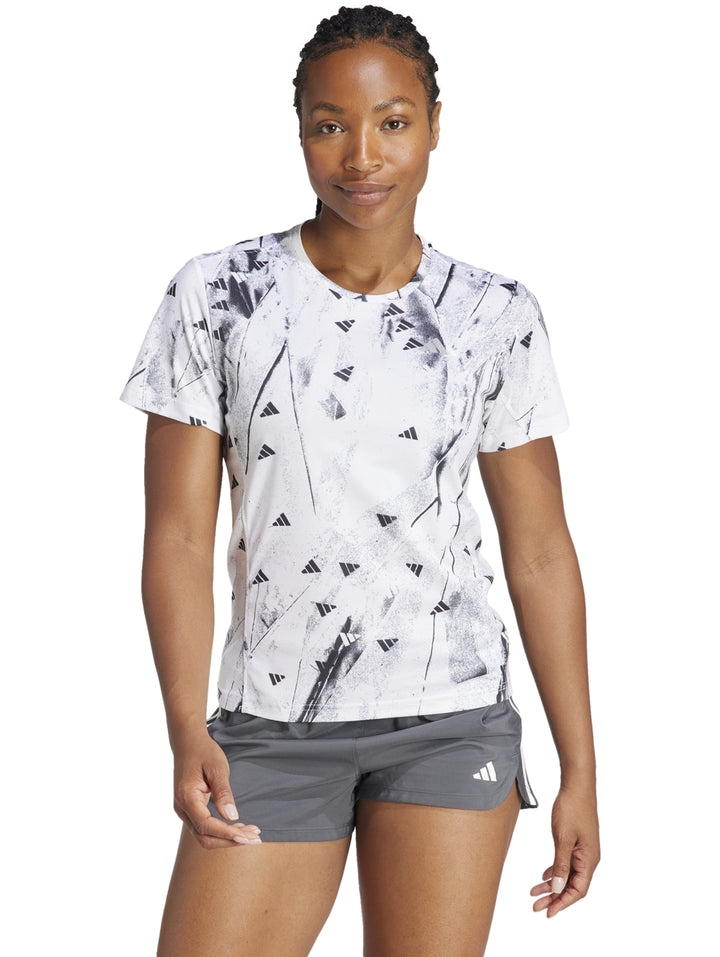 Camiseta deportiva blanca de manga corta con estampado abstracto en negro y cuello redondo.