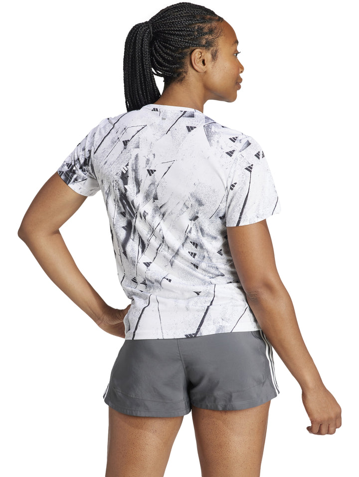 Camiseta deportiva blanca de manga corta con estampado abstracto en negro y cuello redondo.