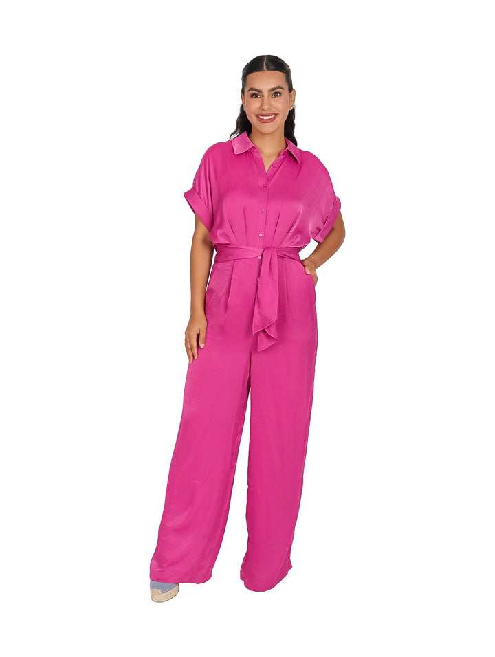 Mujer vistiendo un jumpsuit color rosa brillante con cuello, manga corta y pantalones anchos.