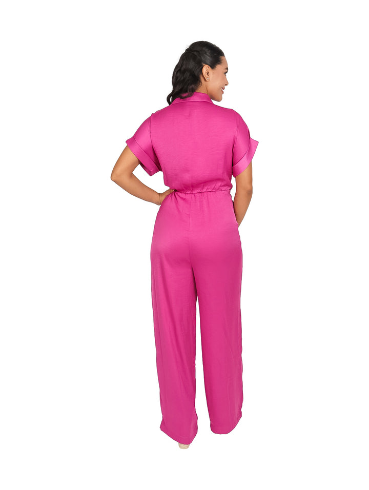 Mujer vistiendo un jumpsuit color rosa brillante con cuello, manga corta y pantalones anchos.
