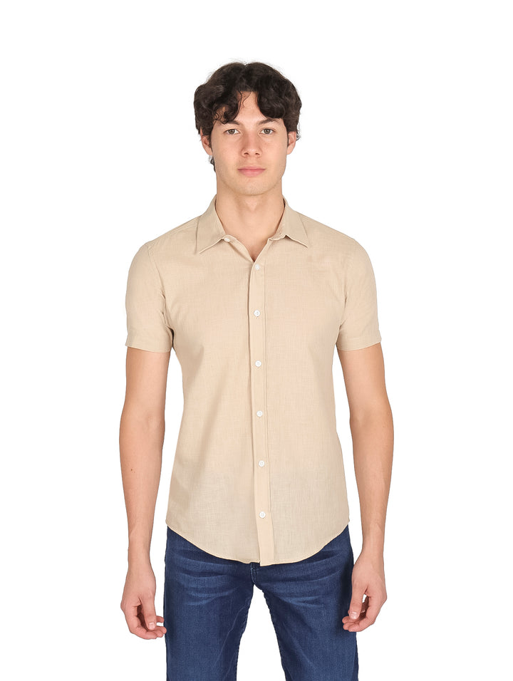 Hombre vistiendo una camisa de manga corta color kaki con corte slim fit y pantalones azules.