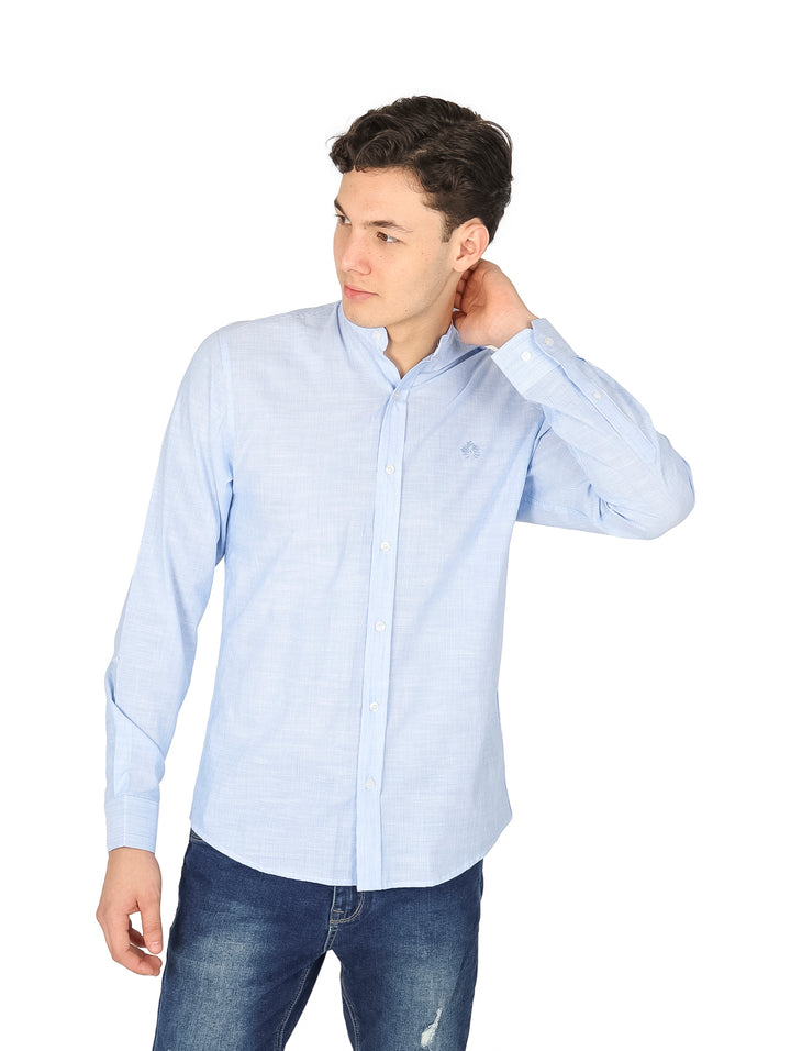 Hombre vistiendo camisa slim azul claro de manga larga con cuello mao y pantalones jeans azules.