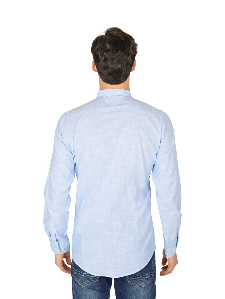 Hombre vistiendo camisa slim azul claro de manga larga con cuello mao y pantalones jeans azules.