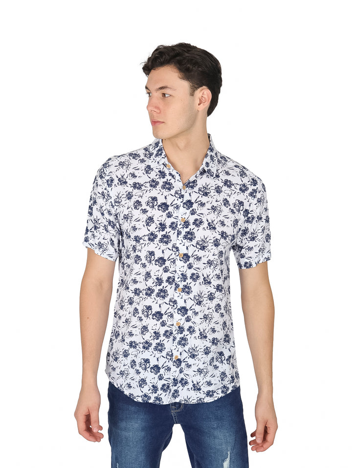 Hombre vistiendo camisa blanca de manga corta con estampado floral marino y pantalones vaqueros.
