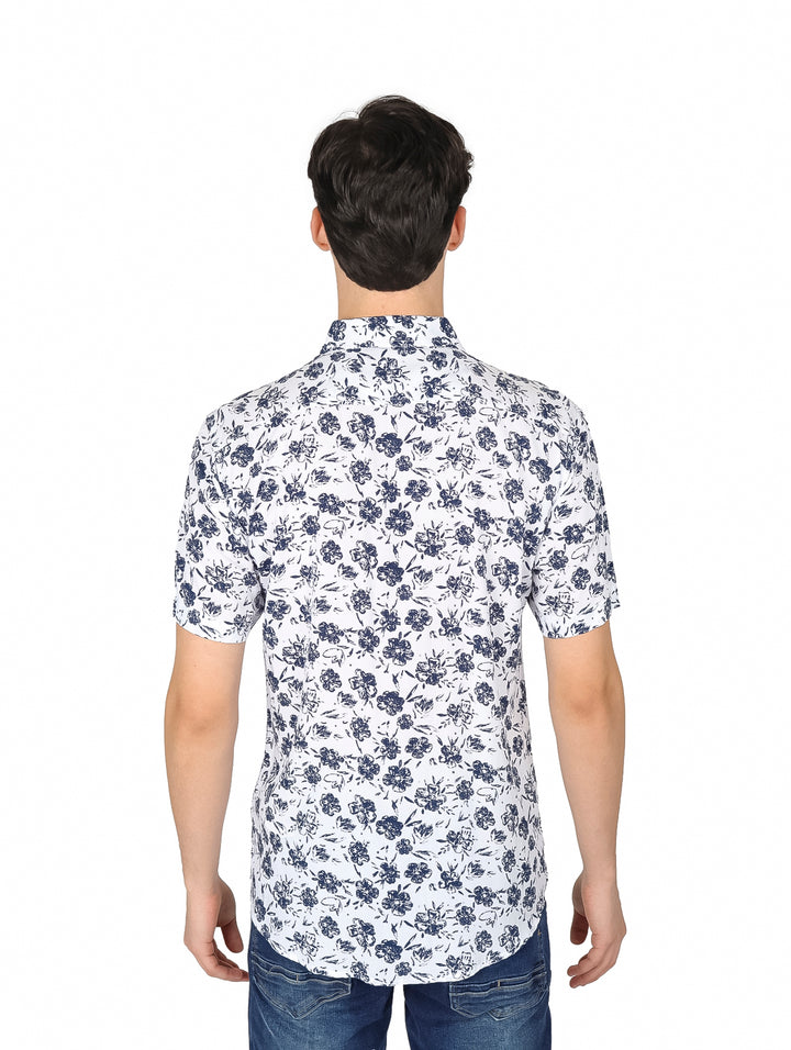 Hombre vistiendo camisa blanca de manga corta con estampado floral marino y pantalones vaqueros.