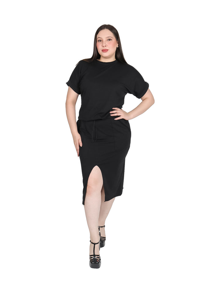 Mujer vistiendo un conjunto negro de camiseta y falda midi con abertura lateral.
