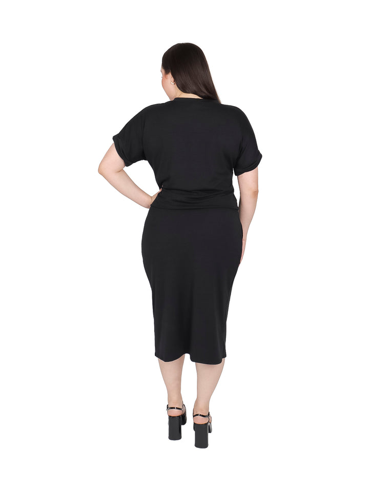Mujer vistiendo un conjunto negro de camiseta y falda midi con abertura lateral.