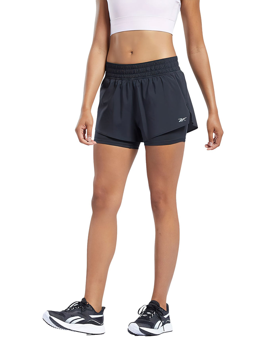 Mujer vistiendo shorts deportivos Reebok 2 en 1 de color negro para running.