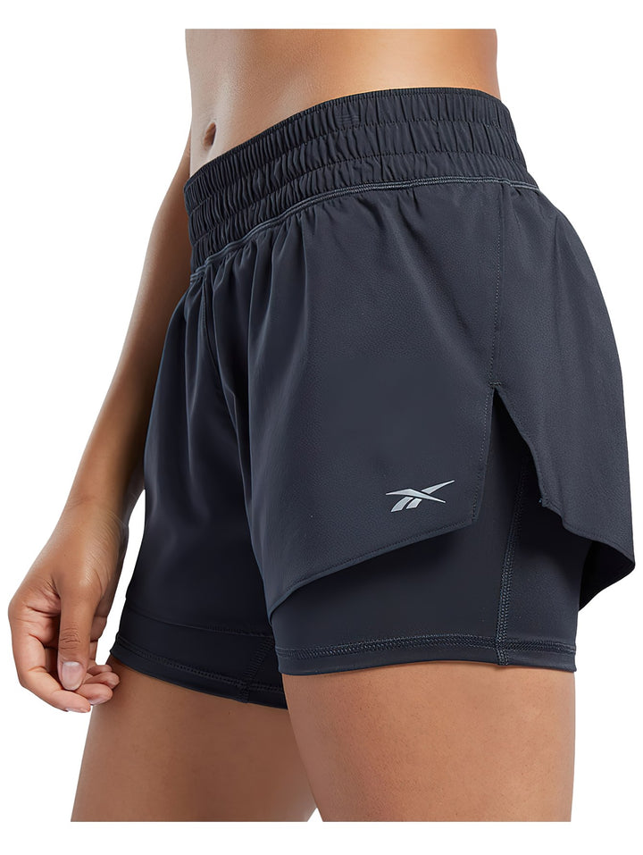Mujer vistiendo shorts deportivos Reebok 2 en 1 de color negro para running.