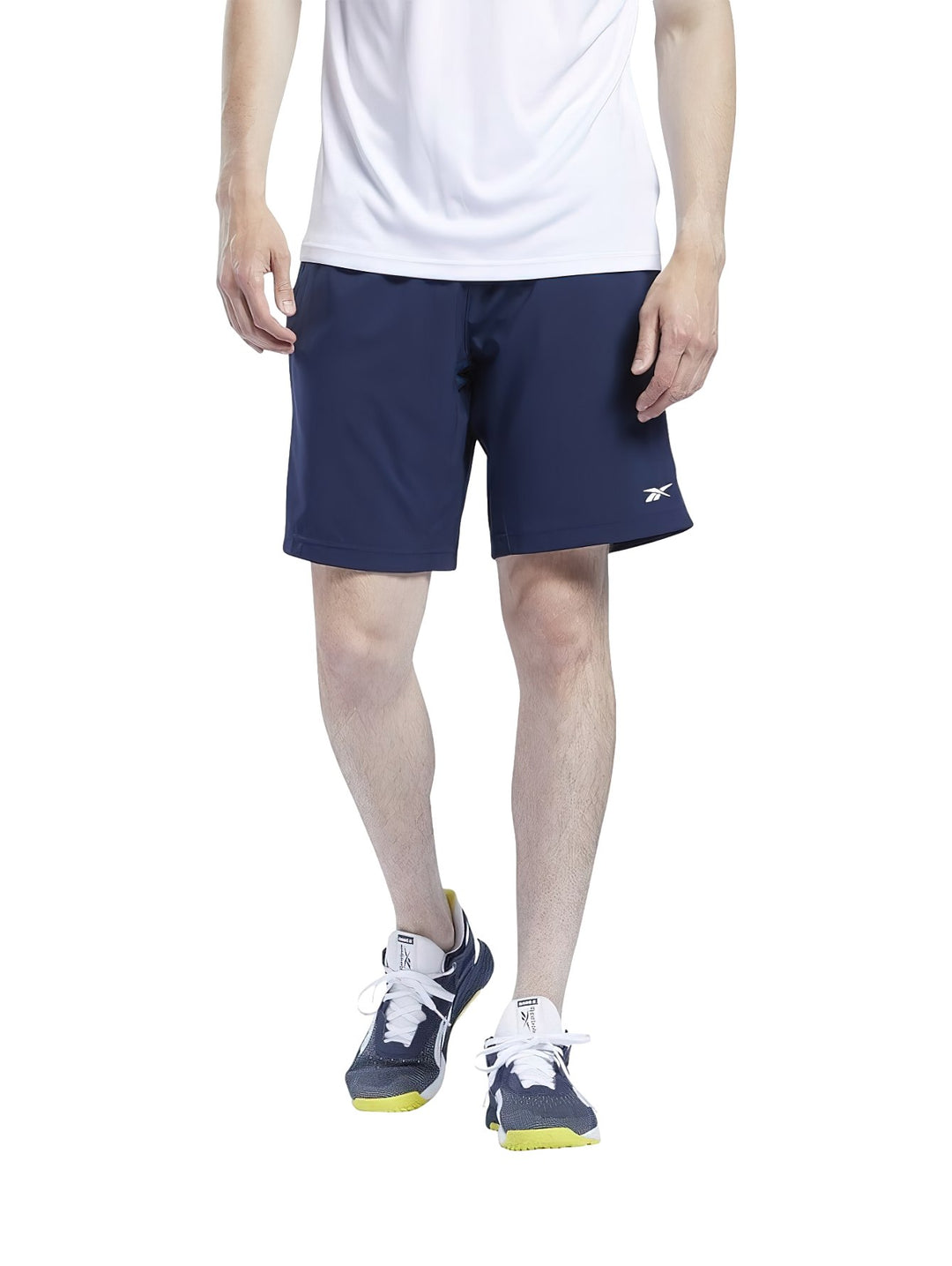Hombre vistiendo shorts deportivos Reebok en color azul marino y camiseta blanca.