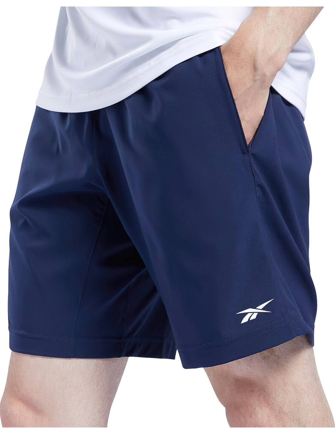 Hombre vistiendo shorts deportivos Reebok en color azul marino y camiseta blanca.