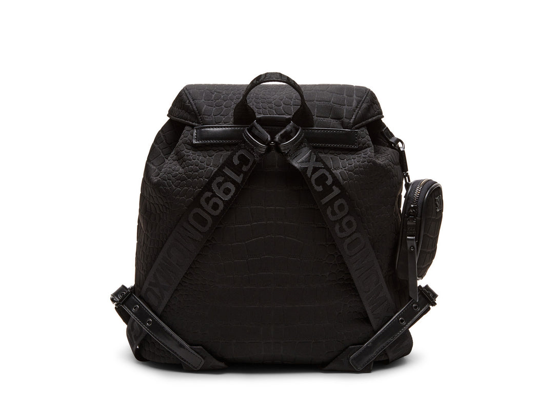 Mochila negra Steve Madden con textura rugosa, bolsillos frontales con hebillas plateadas y un pequeño bolso lateral.
