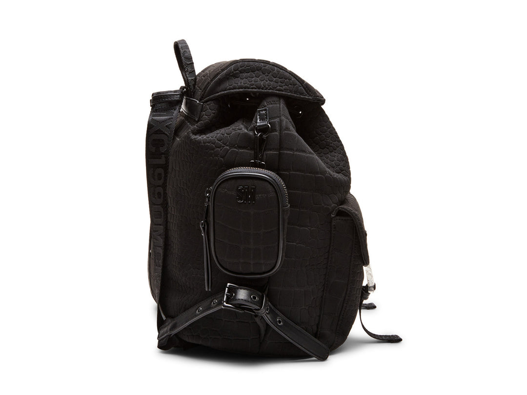 Mochila negra Steve Madden con textura rugosa, bolsillos frontales con hebillas plateadas y un pequeño bolso lateral.